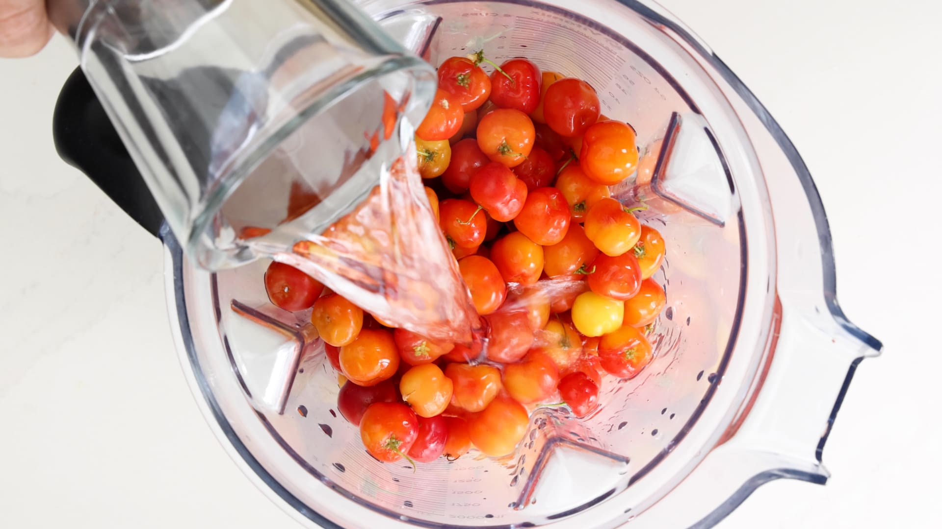 Adding water to the blender with acerola.