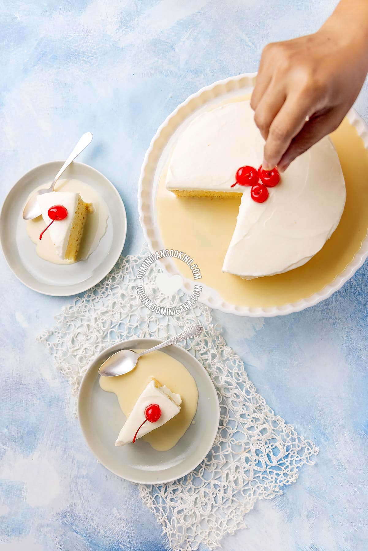 Hand putting cherry on tres leches (three-milk cake).